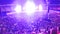 Out of focus image of big crowd of fans sitting on stadium seats watching and listening rock concert at night.