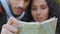 Out of focus young hispanic couple backpackers looking at paper map looking for right route man and woman hiking