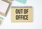 out of office text on craft colored notepad