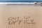 Out of office written in the sand on a beach