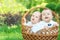 Outdoor activity for families with kids: Portrait of two little infant boys sitting in wicker basket on grass on picnic