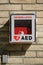 Outdoor AED cardiac defibrillator box isolated on brick background