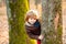 Outdoor autumn kids portrait. Cute little kid boy enjoying climbing on tree. Child in autumnal clothes learning to climb