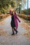 Outdoor autumn portrait of happy smiling plus size red hair woman in coat walking in fall park.