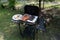 Outdoor barbecues. Sausages, black pudding, onions and baked bread on the grill. Food baked on aluminum foil tray