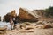 Outdoor beach wedding ceremony near the ocean, romantic happy couple sitting on stones at the beach