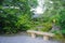 Outdoor bench, green plants, road and pavilion in Japanese zen g