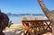 Outdoor cafe on the beach. Empty table and chairs on seashore. Outdoor tropical restaurant with boats and isles on background.