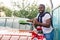 Outdoor car wash with sponge and foam. Car washing. Smiling African man showing thumb up, cleaning his car windscreen