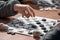 Outdoor checkers tournament on paper checkerboard on table, close up players hands