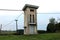 Outdoor concrete electricity substation building with dilapidated facade and metal doors surrounded with wires and leaning wooden