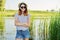 Outdoor country portrait of teenage girl in hat sunglasses near pond in the reeds