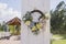 Outdoor Country Wedding Scene with Wooden Door, Gazebo and Wreath with Yellow Roses