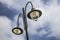 Outdoor Double Lamp Post Fixture. Street Light Standing High against Cloudy Sky on Fair Day. Two Inverted Pendant with