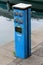 Outdoor electrical outlets with safety switches mounted on blue metal pole used for powering small boats in local harbor