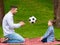 Outdoor family hobbies. Young dad teaching his little son play soccer on picnic in public park