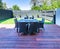 Outdoor furniture - dining table with chairs on a wooden deck at townhouse back yard.