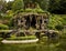 Outdoor gazebo built on a man made cave in a garden with a pond