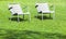 Outdoor gray metal chairs stand on fresh grass