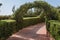 Outdoor Green secret garden with arched entry and gate. Tiled park path in a tunnel under an arch entwined with tropical