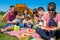 Outdoor group portrait of happy company having picnic on green grass in park and enjoying watermelon