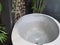 Outdoor hotel 's bathroom with big terrazzo basin bathtub surrounded by trees.