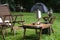 Outdoor kettle, portable gas stove, bowl and vintage lanterns with outdoors table set on green lawn in camping area