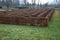 Outdoor maze for kids. he planted hornbeams in a row in a hedge. the plants are mulched. there is a gray gravel road between the l