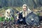 Outdoor northern warrior woman with braided hair and war makeup holding shield and ax with wolf next to her ready to attack -