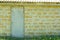 Outdoor old facade white closed door on ecological shells brick yellow wall background, copy space