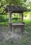 An outdoor old-fashioned, old hand made water well with a wooden roof in the garden. Restoring an old water well