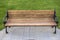 Outdoor park bench with black cast iron rails, legs and feet.  The Sitting and back supported by wooded planks