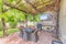 Outdoor patio with covered barbecue grill under a pergola roof with vines
