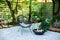 Outdoor patio furniture on pebbles in a front garden. Front veranda of house with black Acapulco armchair, coffee table and plants