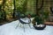 Outdoor patio furniture on pebbles in a front garden. Front veranda of house with two black Acapulco armchairs, coffee table and p