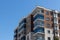 An outdoor perspective shoot to corner of a modern building with brown and white colors - clean blue background