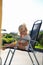 Outdoor photo of cute little girl having sunbath at chair