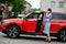 Outdoor photo of gorgeous woman posing near orange suv car with open door, speak on phone