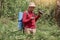 Outdoor photo of man with compass and binovulars in hands, traveler on wooden background wearing red casual shirt, finding way to