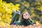 Outdoor photo of young beautiful teenager girl surrounded autumn leaves.