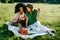 Outdoor picnic portrait. Two multi-race girl friends are having fun.The alluring african girl is browsing via the mobile
