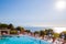 Outdoor pool with vibrant crystal water, parasols and deck chairs located on the coast of Garda with lake, hills and sun on