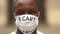 Outdoor portrait of a African American in a medical mask with the inscription I cant breathe. Black lives matter, mass