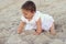 Outdoor portrait of a beautiful baby on all fours on the sand