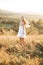 Outdoor portrait of a beautiful blond woman walking in summer field at sunset. Model attractive sexy girl with boho