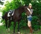 Outdoor portrait of beautiful cowgirl with horse in green