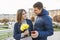 Outdoor portrait of beautiful romantic couple, young man and woman with bouquet of yellow flowers of daffodils and looking in