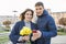 Outdoor portrait of beautiful romantic couple, young man and woman with bouquet of yellow flowers of daffodils and looking in
