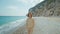 Outdoor portrait beautiful summer woman walking pebble beach and enjoying weekend at seaside with cliffs by the sea