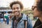 Outdoor portrait of charming african-american man walking with friend in park, wearing denim clothes and headphones over